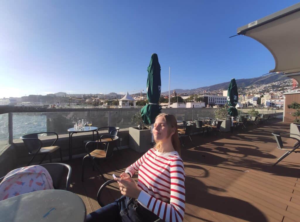 Valeria sitting in cafe by the ocean in Madeira Island Portugal in January
